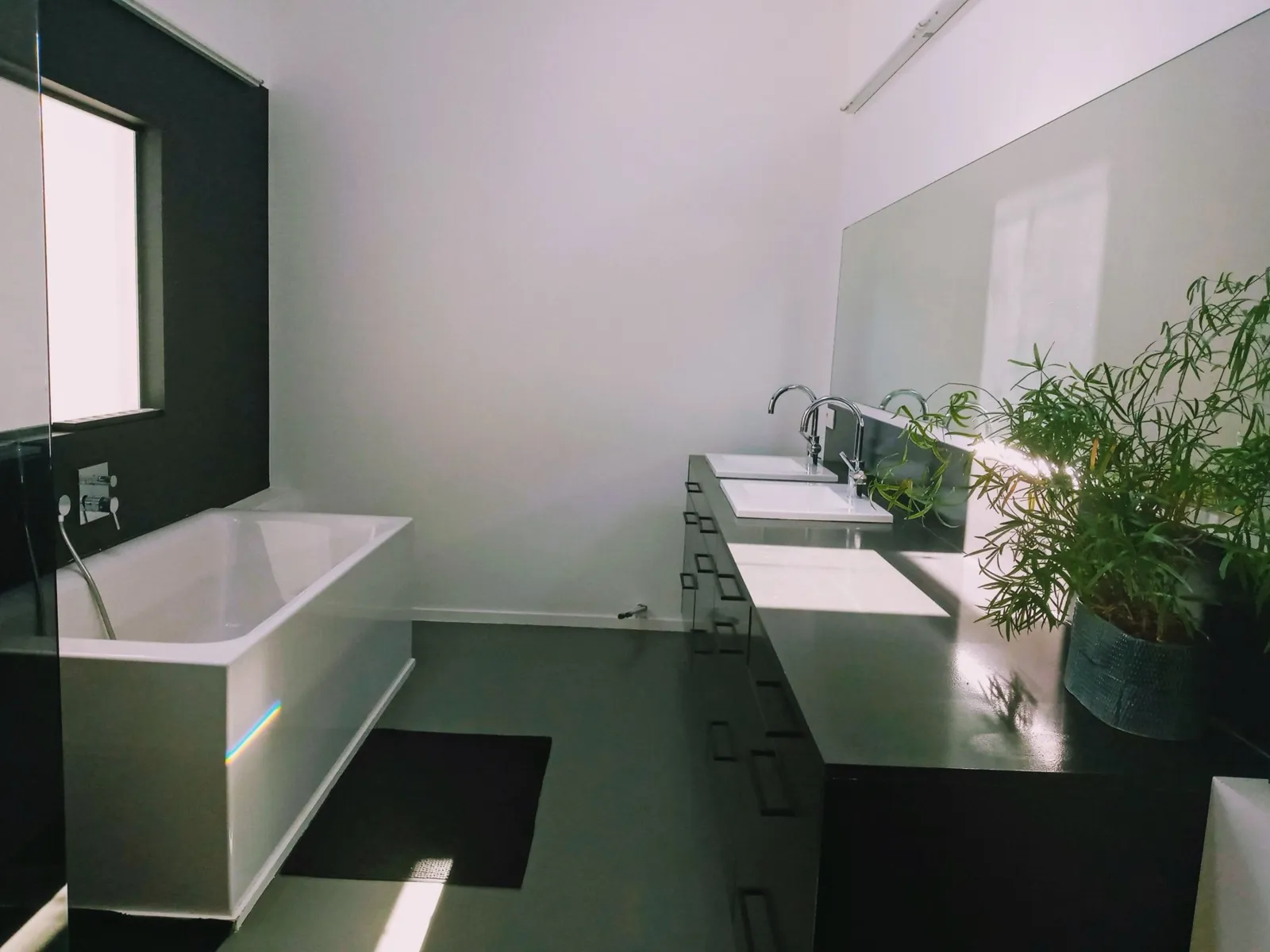 Badkamer met bad en dubbele wastafel in ochtendlicht