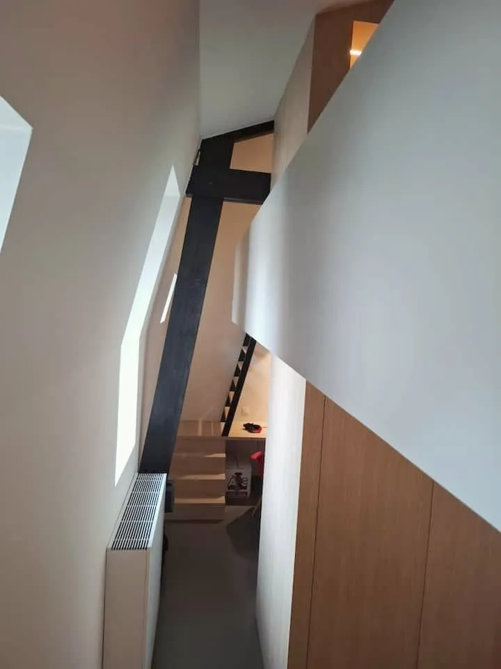 Steile trap en zwarte balk naar een slaapmezzanine
