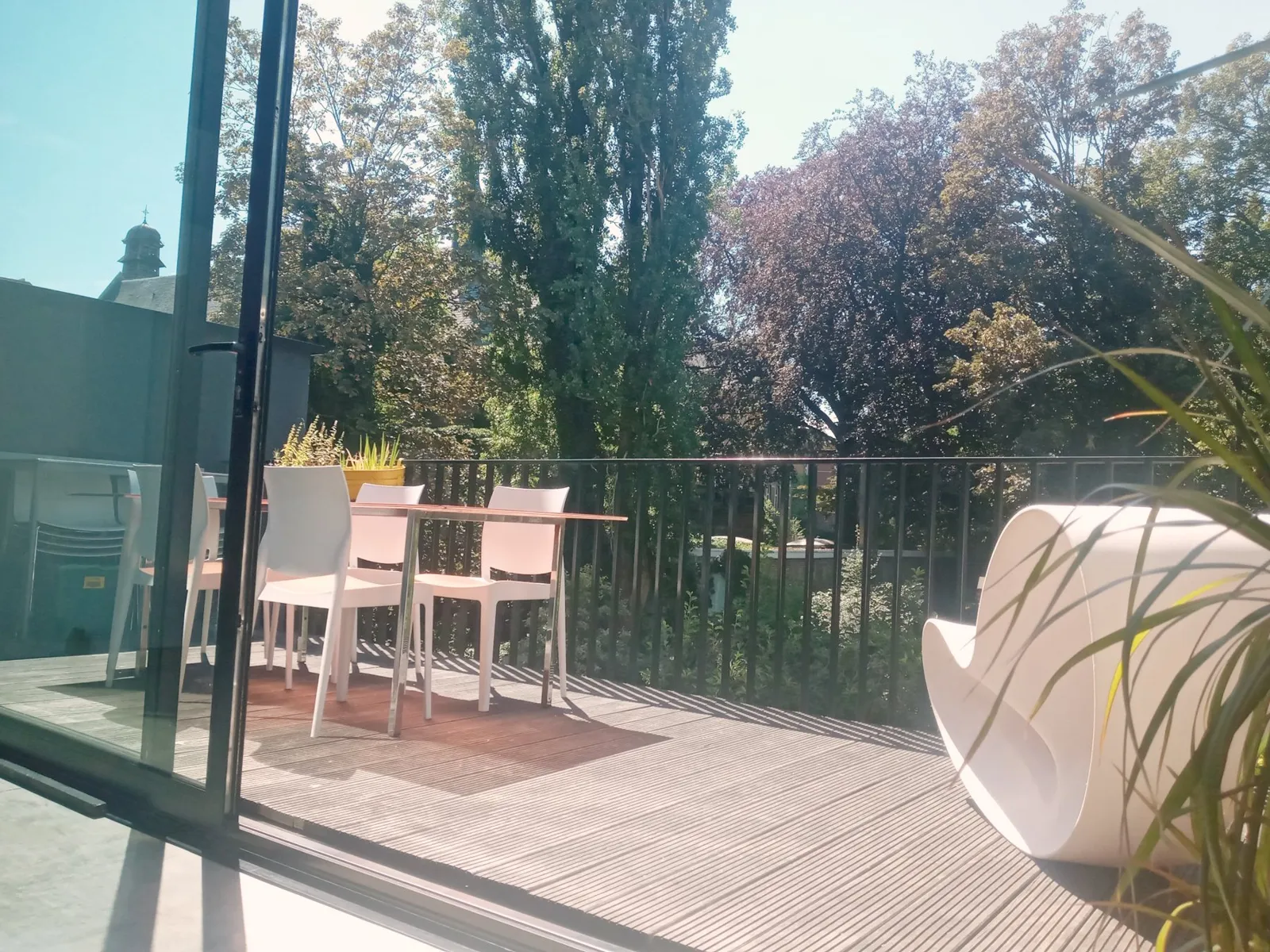 Keukenterras met tafel en stoelen onder hoge bomen